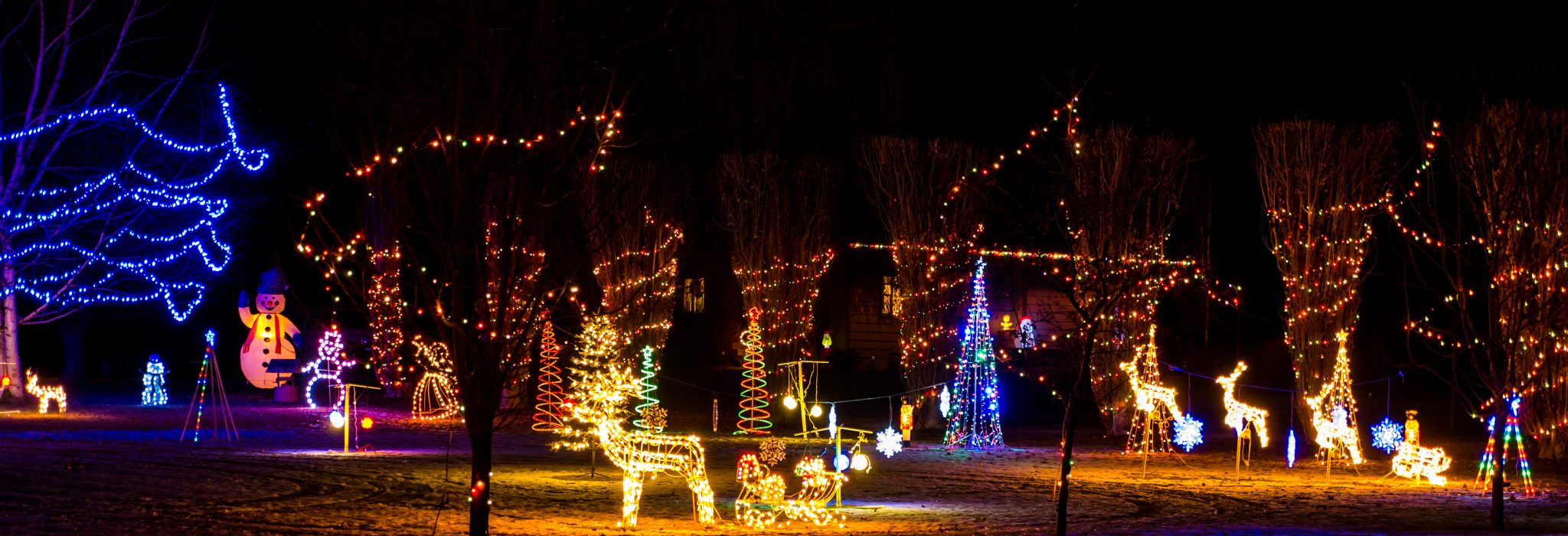 A Christmas light display in the front yard of a home on the drive of a Christmas lights trail.